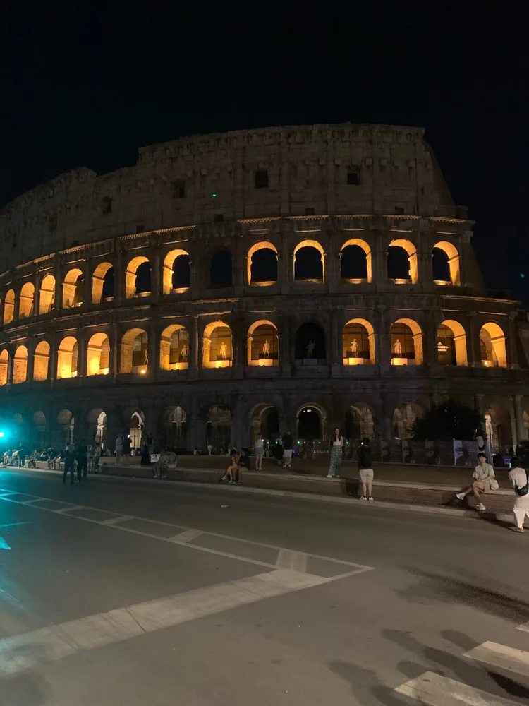 Das Kolosseum bei Nacht beleuchtet, mit goldenen Arkaden